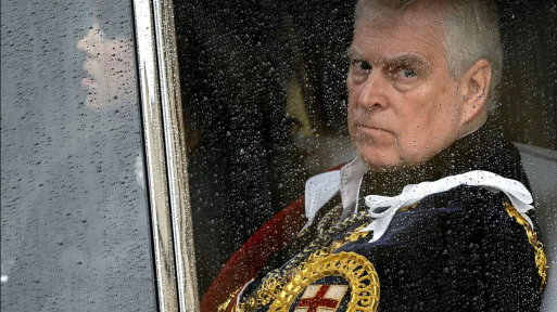 Reuters Prince Andrew sitting behind a glass window in a car with raindrops on it. He is looking glum and wearing a royal uniform with golden trim and a St George's cross on it.